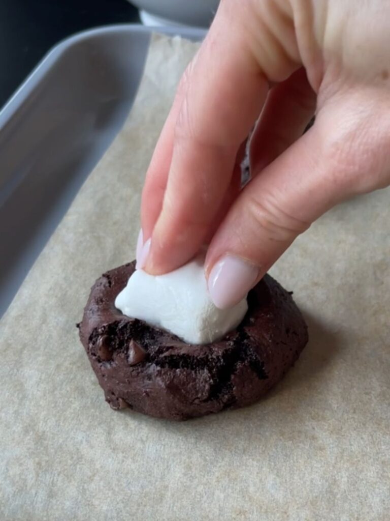 pressing a marshmallow into the gluten free chocolate cookies