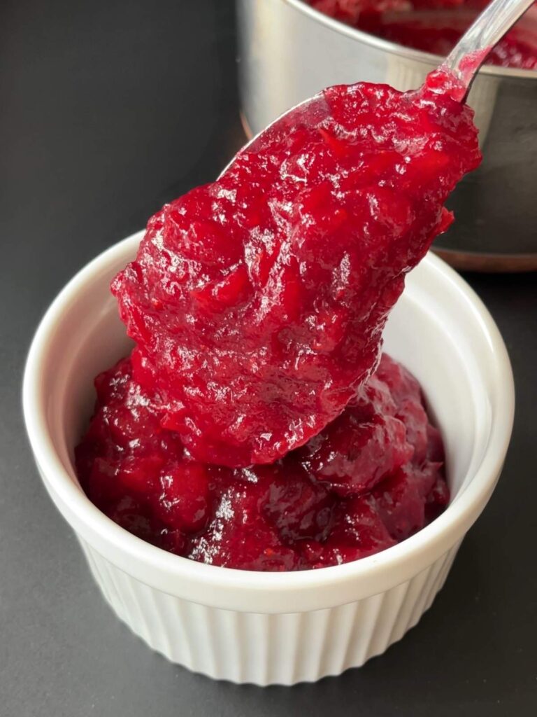 transferring the cranberry sauce from the saucepan to a serving bowl