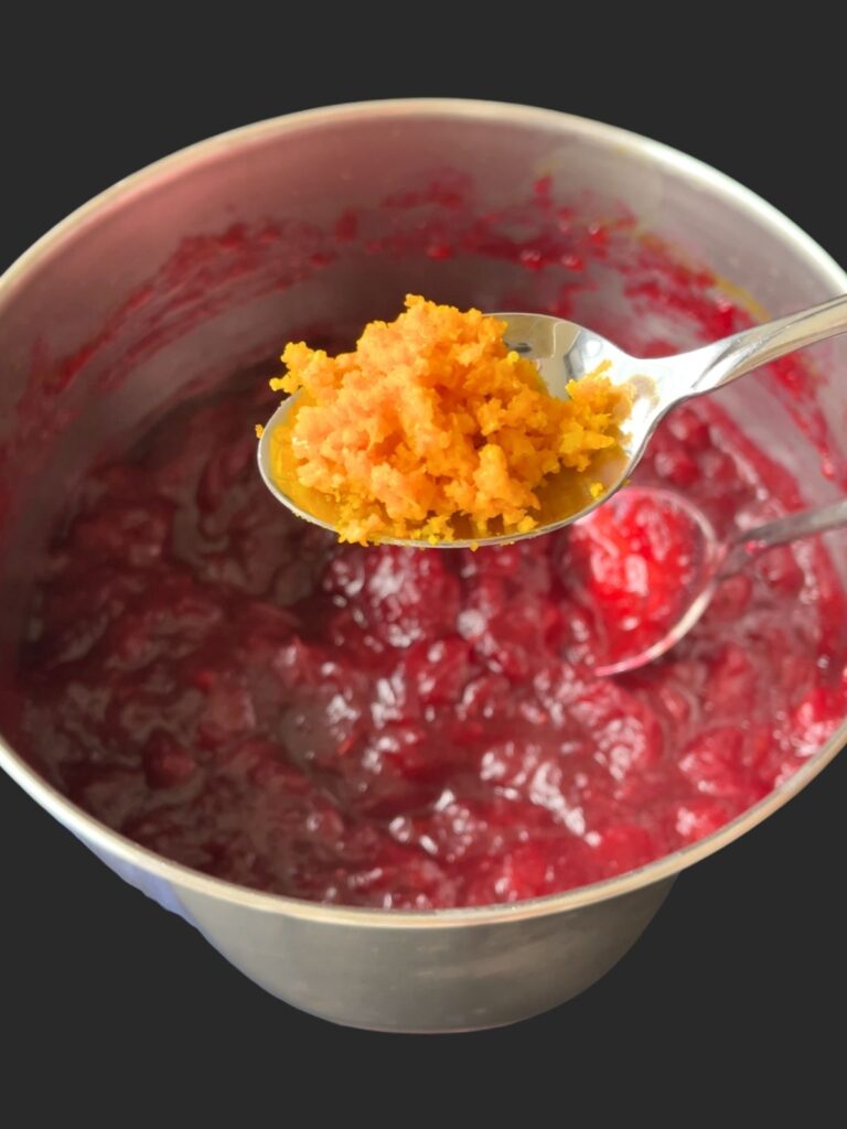 adding a spoonful of orange zest to the cranberry sauce
